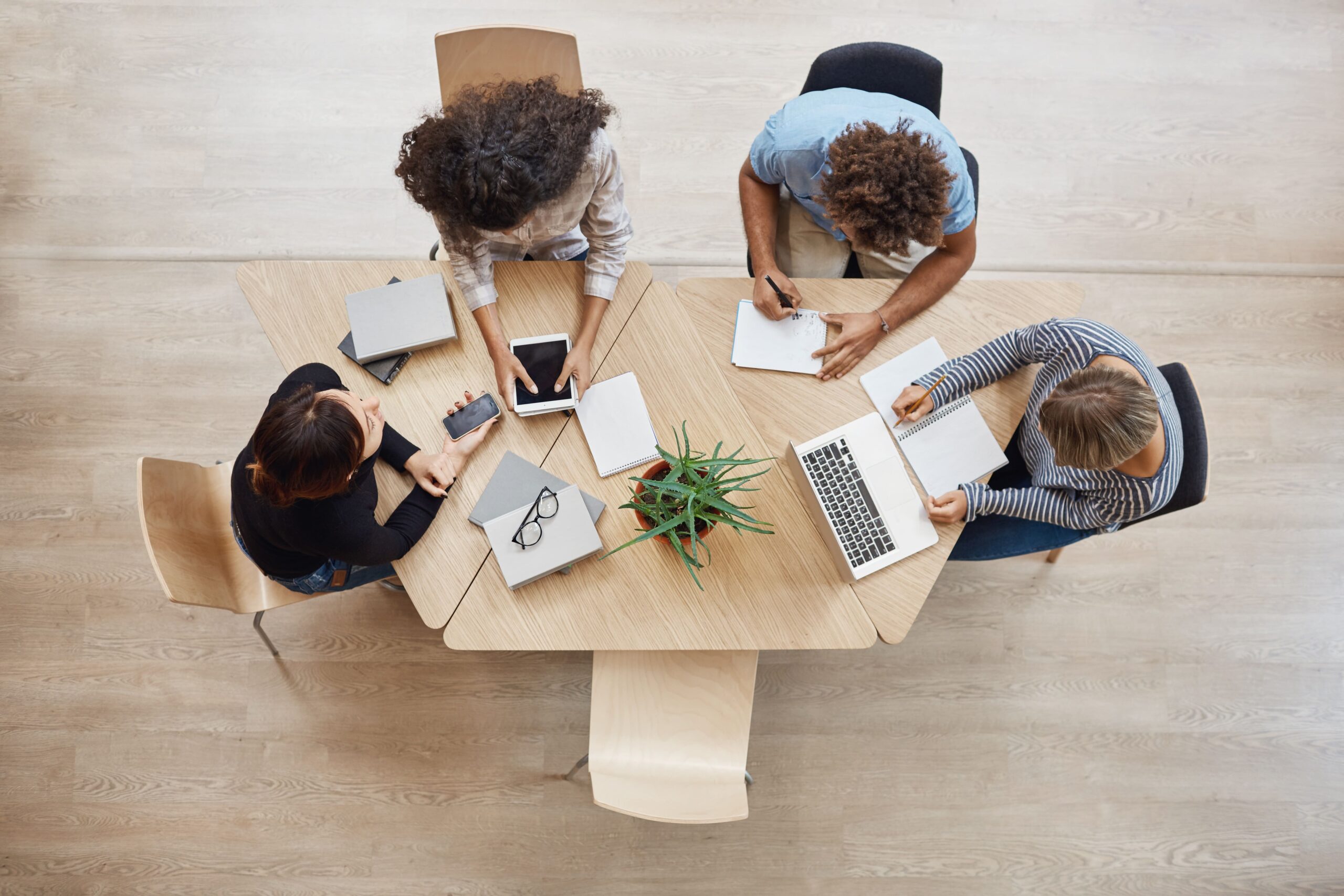 Four team members working on a triangle shaped wooden desk