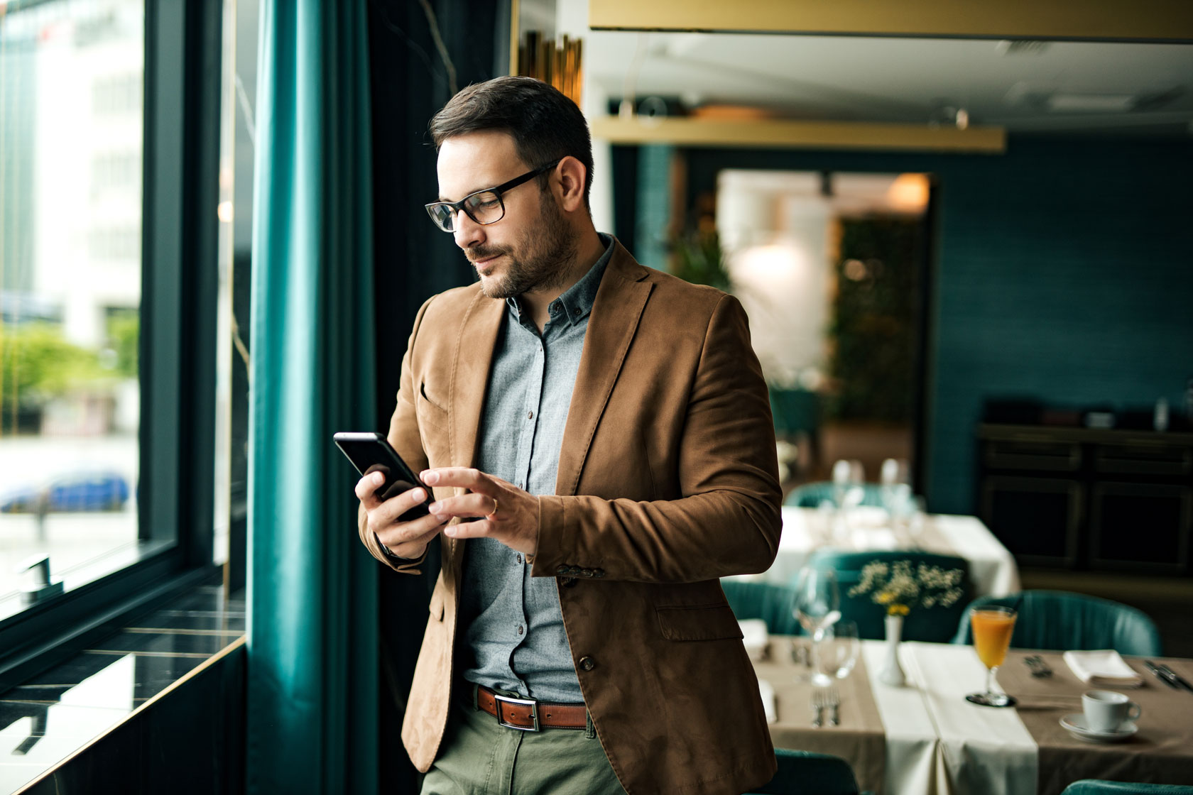 Finance consultant checking his phone while standing in a restaurant